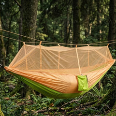 Hamac de survie moustiquaire suspendu entre deux arbre dans une forêt 